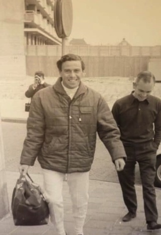 Jim arrive sur un circuit avec sa combinaison et son sec contenant ses gants ,ses chaussures et son casque